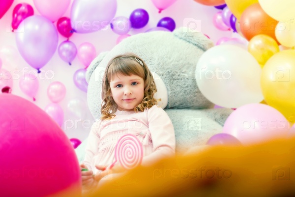 Cute girl posing in playroom on balloons backdrop