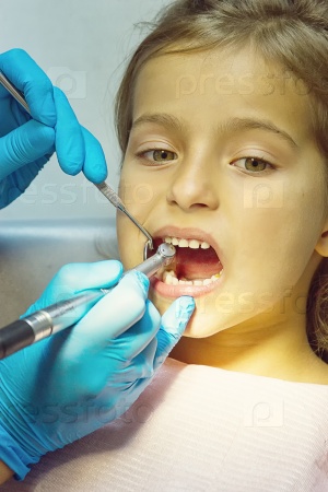Girl is having her teeth examined by dentist