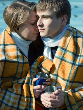 loving couple in a blanket in winter drink tea