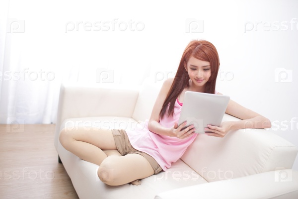 happy woman using tablet pc on sofa in the living room, asian beauty