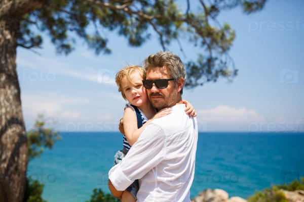 Father and son hugging on the blue sea background