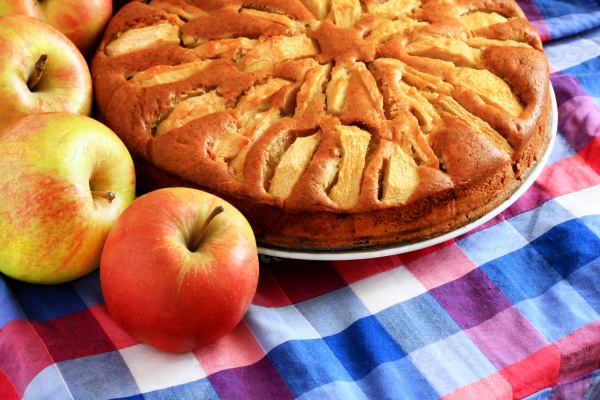 Freshly baked apple pie with apples in the background