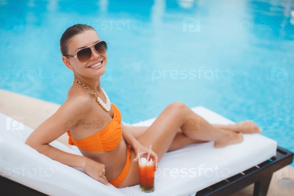 Sexy young woman relaxing on deck chair. sexy girl in bikini lying near swimming pool. photo from upper point. Woman sunbathing in bikini at tropical resort. Beautiful woman lying on sun lounger