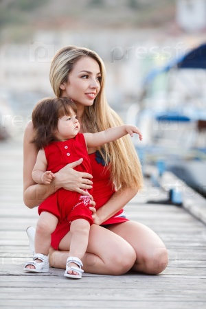 Mother and daughter having fun on wooden bridge by the sea. Happy Family by the Sea. mother playin with baby girl. Woman with child in marine sea style