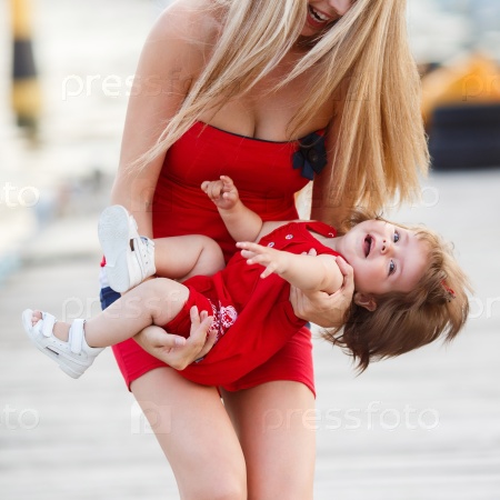 Mother and daughter having fun on wooden bridge by the sea. Happy Family by the Sea. mother playin with baby girl. Woman with child in marine sea style