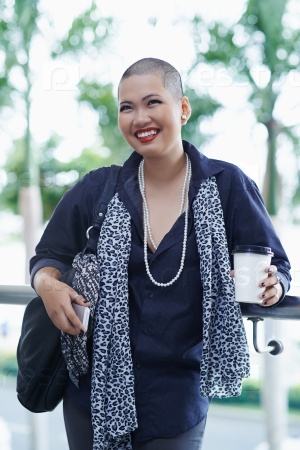 Portrait of beautiful Asian woman with shaved head standing outdoors
