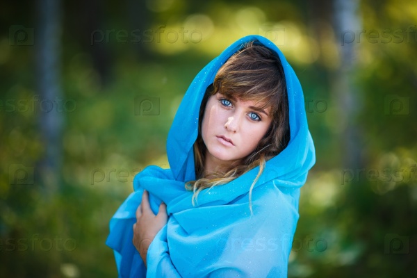 Portrait of attractive young girl in blue sari covered her head in a forest, stock photo