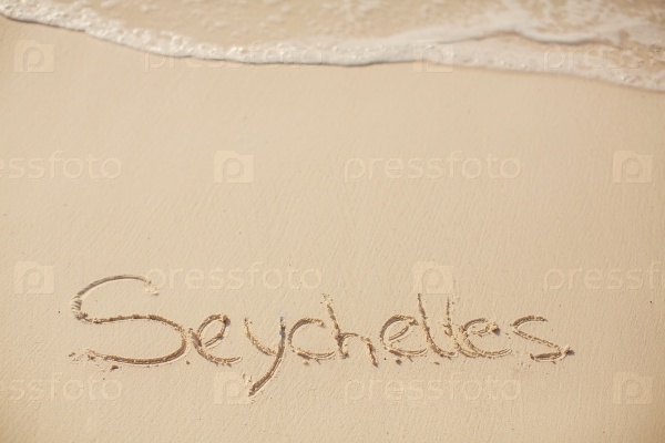 water surf edge on beach sand, concept holiday background with seychelles inscription