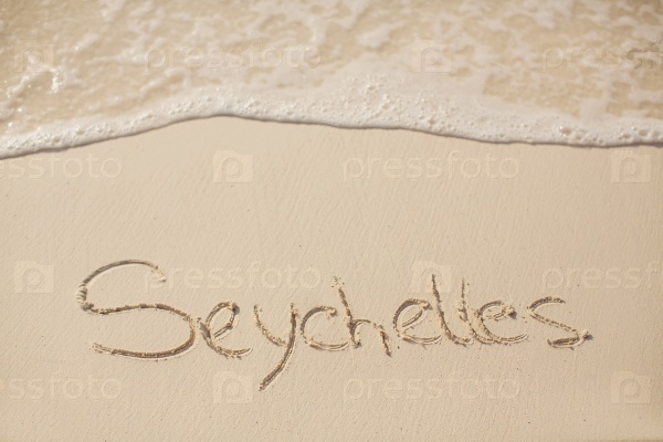 water surf edge on beach sand, concept holiday background with seychelles inscription