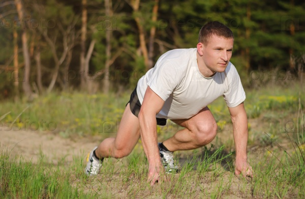 Young athletic man at the start to run outdoors.