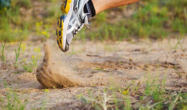 Athlete\'s foot in sneakers which starts to run. Sand flies under their shoes. Foot motion blur.