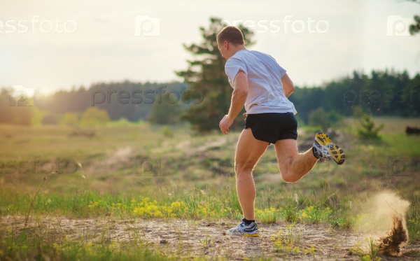 Young man running outdoors. Because of the strong push from under the foot soles of the sand flies.