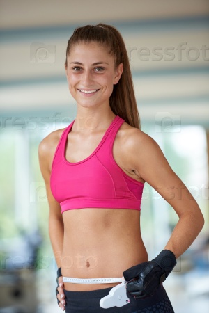young fit woman measuring belly on a training  in  fitness gym