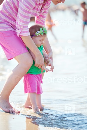 happy mom and baby on beach  have fun while learning to walk and  make first steps