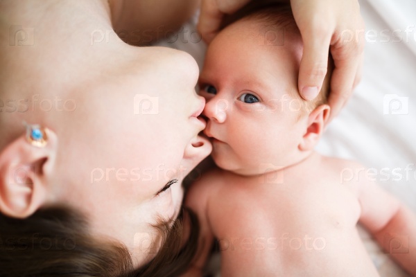 Mother kissing her one month old son in studio