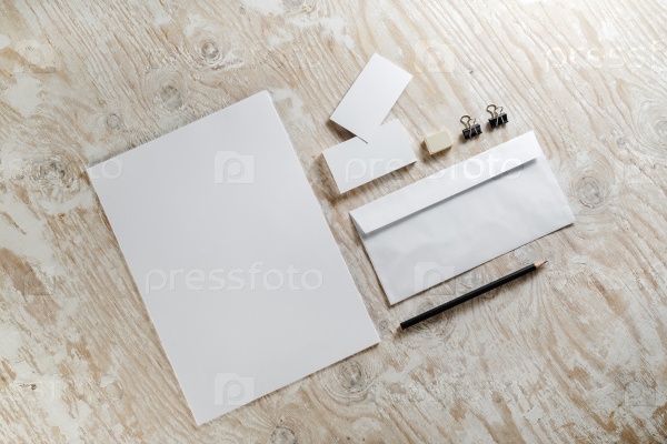 Photo of blank stationery set on light wooden background. Blank template for design presentations and portfolios. Top view.