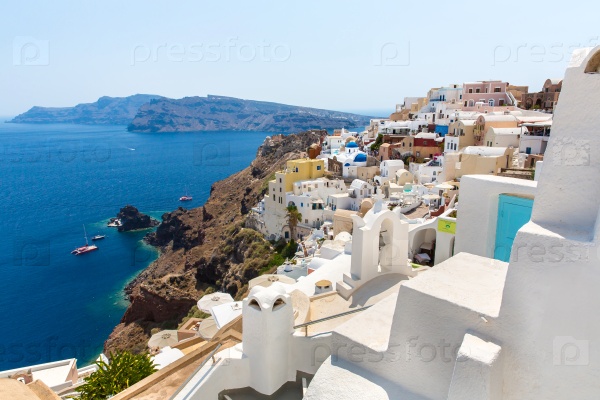 View of Fira town - Santorini island, Crete, Greece. White concrete staircases leading down to beautiful bay with clear blue sky and sea
