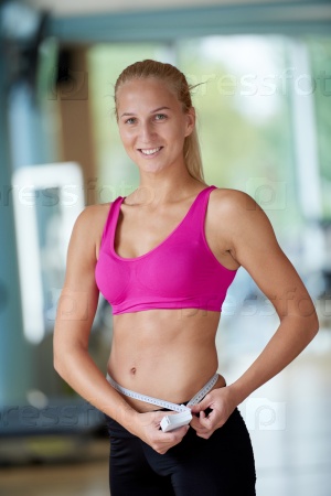 young fit woman measuring belly on a training  in  fitness gym