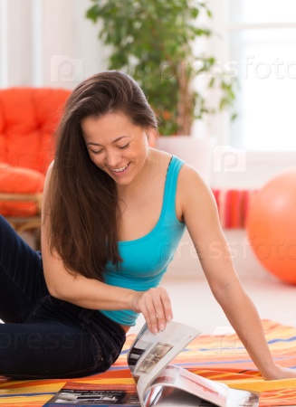 Young beautiful asian woman reading journal at home