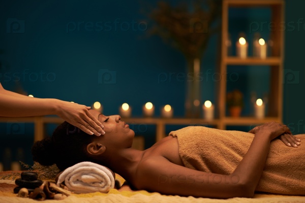 Side view of young woman enjoying massage in luxury spa resort