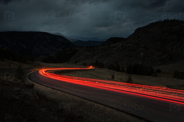 Track on night road against the night sky. Mountain landscape