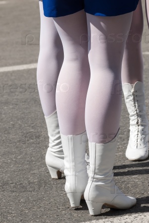 Attractive legs of young women in white boots standing on street