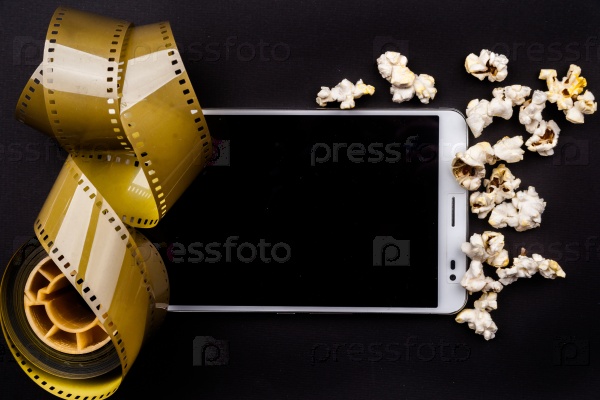 Tablet pc on dark background with attributes of cinema. Visual metaphor for content consumption - films and media on a mobile device.