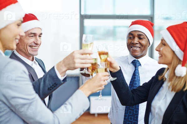 Happy colleagues in Santa caps toasting with champagne
