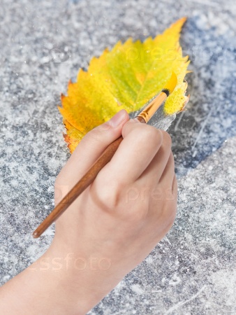 paintbrush paints fallen leaf in yellow colour
