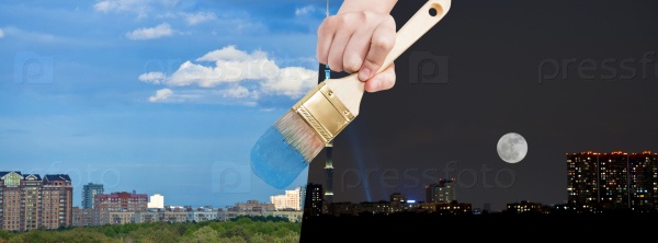 nature concept - seasons and weather changing: hand with paintbrush paints blue sky over daily city from night time