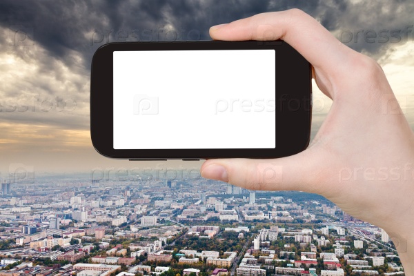 travel concept - hand holds smartphone with cut out screen and storm clouds over city on background