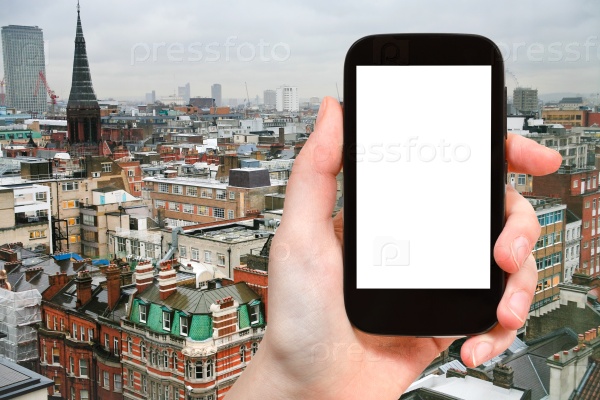 Travel concept - hand holds smartphone with cut out screen and London skyline on background, stock photo