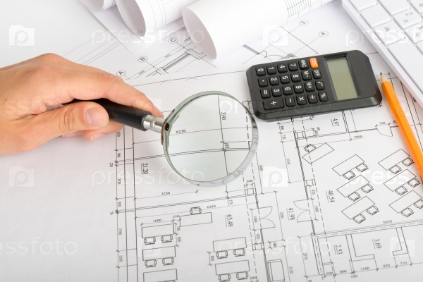 Man looking at draft using magnifier. Calculator and pencil on table, stock photo