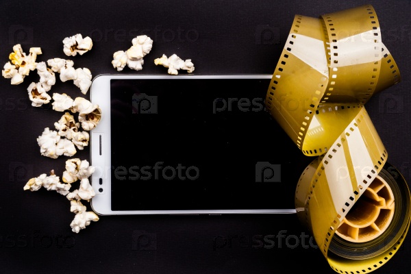 Tablet pc on dark background with attributes of cinema. Visual metaphor for content consumption - films and media on a mobile device.