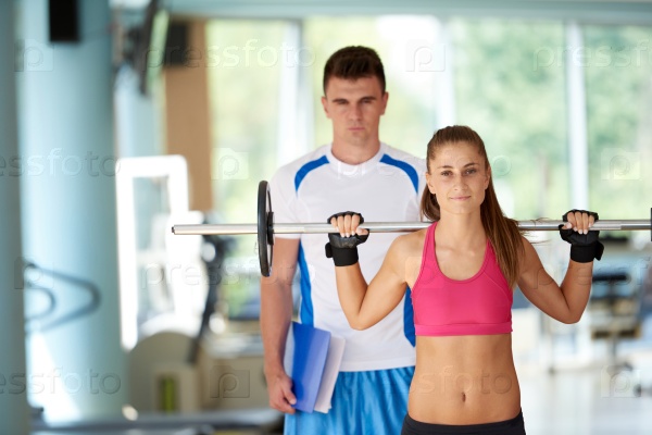 young sporty woman with trainer exercise weights lifting in fitness gym