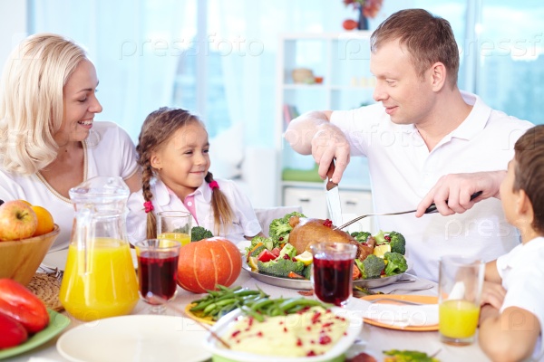 Happy young family celebrating Thanksgiving by festive table