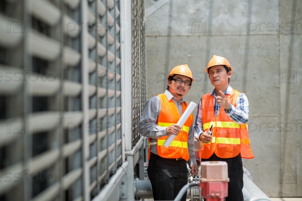 Asian construction workers examining quality of new building