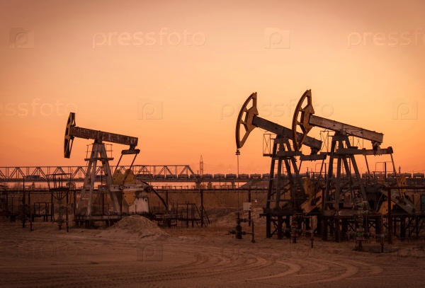Pump jack group on a sunset sky background. Extraction of oil. Toned.