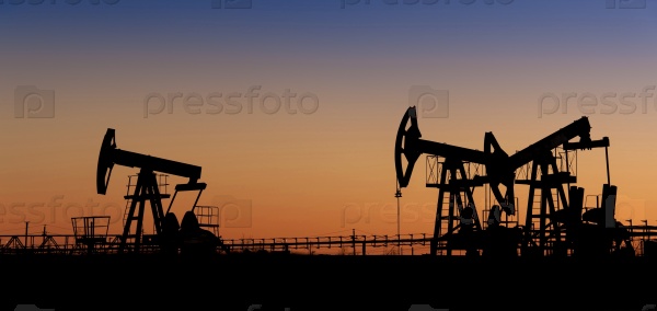 Pump jack group silhouette on a sunset sky background. Extraction of oil. Toned.
