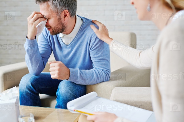 Crying man with handkerchief sitting by his psychologist