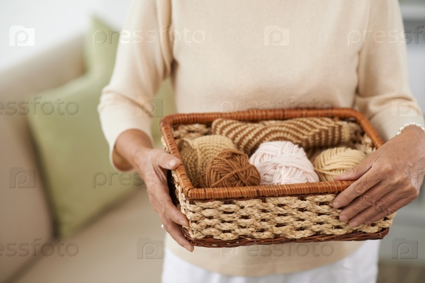 Female hands holding a basket with balls of woolen yarn