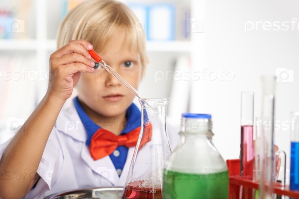 Schoolboy using pipette to add reagent to the flask