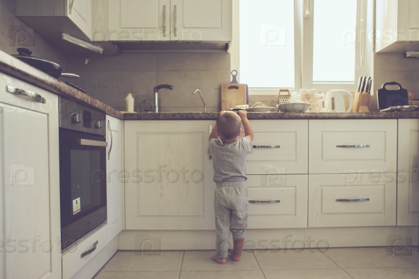 2 years old child standing on the floor alone in the kitchen, casual lifestyle photo series in real life interior