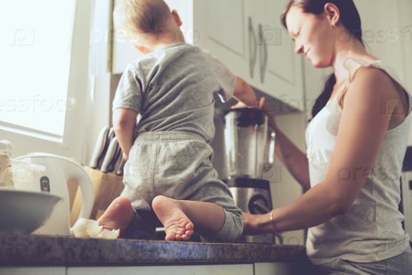 Mom with her 2 years old child cooking holiday pie in the kitchen to Mothers day, casual lifestyle photo series in real life interior. Focus on baby\'s foots.