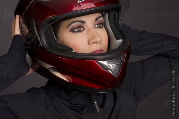 A red full face helmet is put on by a woman rider motorcycle gear