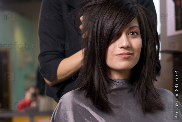 A salon stylist gives woman fluff up at the end of a haircut