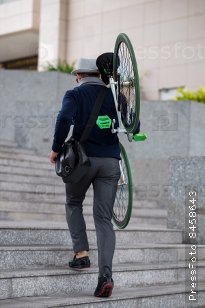 Guy carrying his bike up the stairs, view from the back