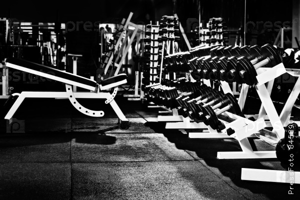 many black dumbbells in dark weight room, horizontal photo