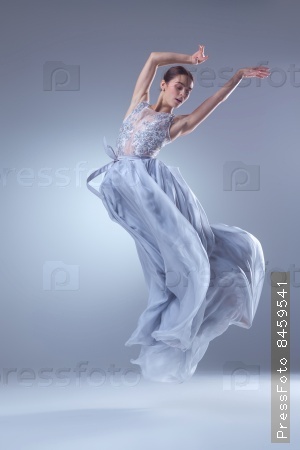 The beautiful ballerina dancing in long lilac dress on lilac background