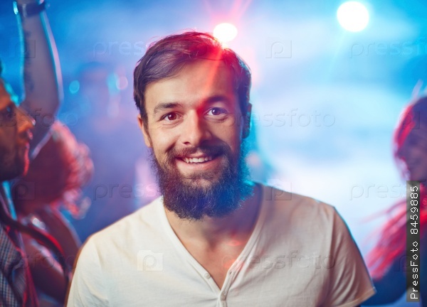 Happy unshaven man looking at camera with smile during party in night club